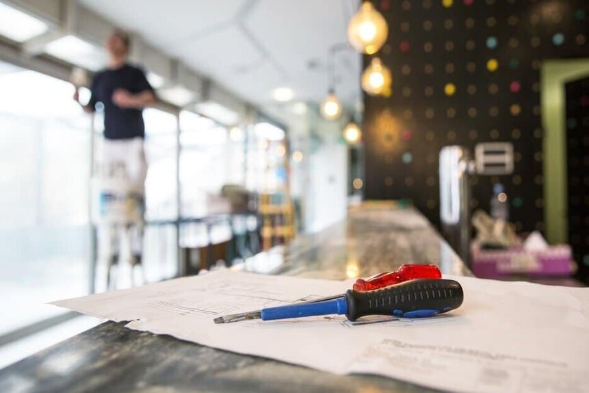Home renovation, man on a ladder with screwdrivers in the foreground