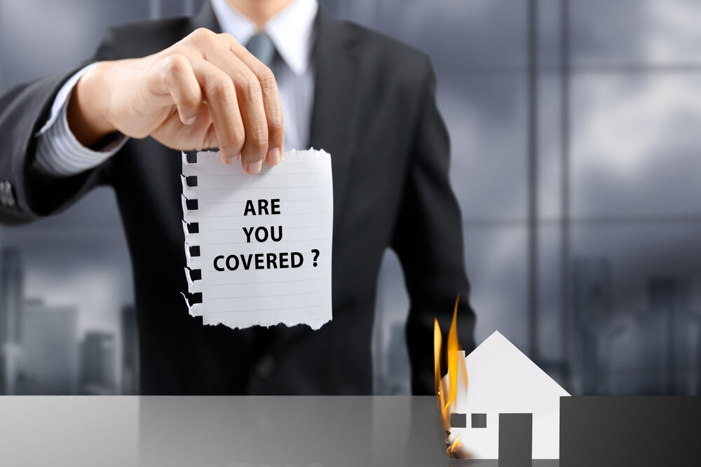 businessman present insurance concept with house on fire